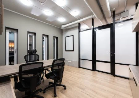 Open-plan office interior with workstations, glass-partitioned cabins and wooden flooring