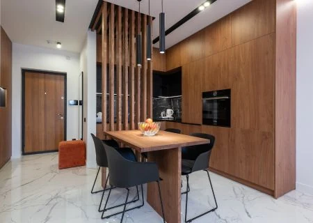 Open-plan kitchen and dining area with a wood-slat partition, dark cabinetry and a timber dining table